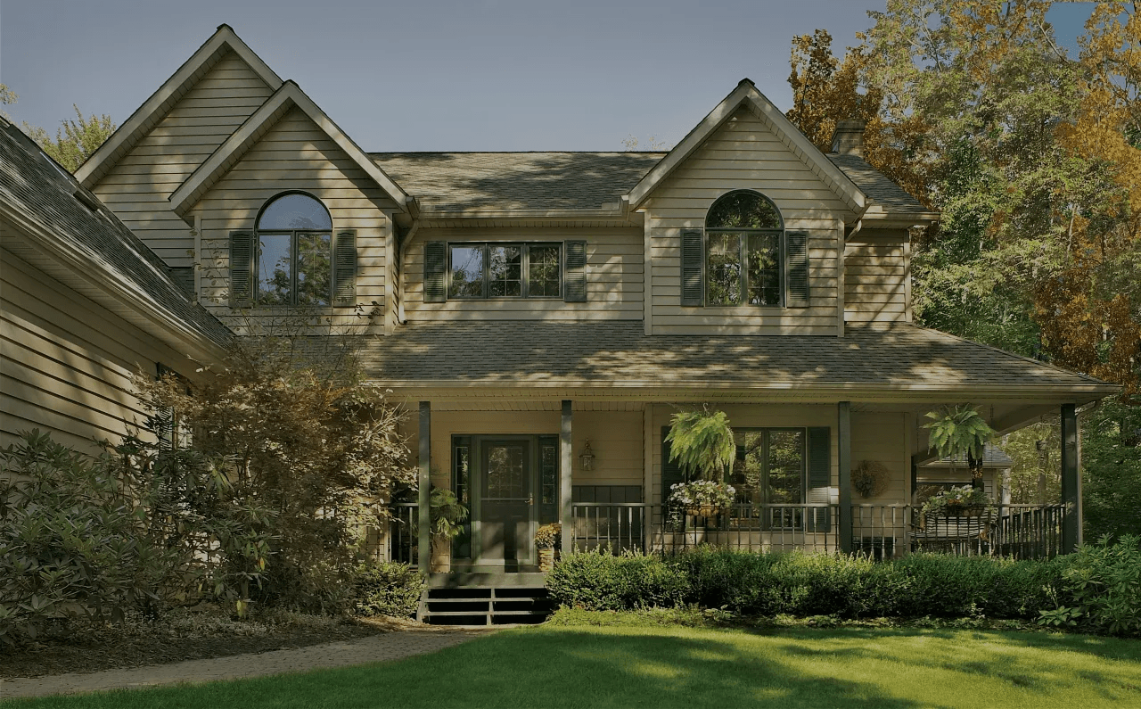 A tan house with new siding and dark green trim.